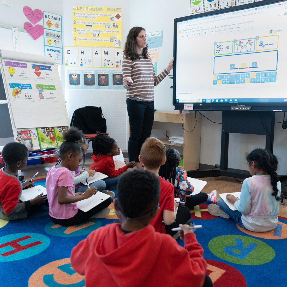 Teacher at white board with young students learning