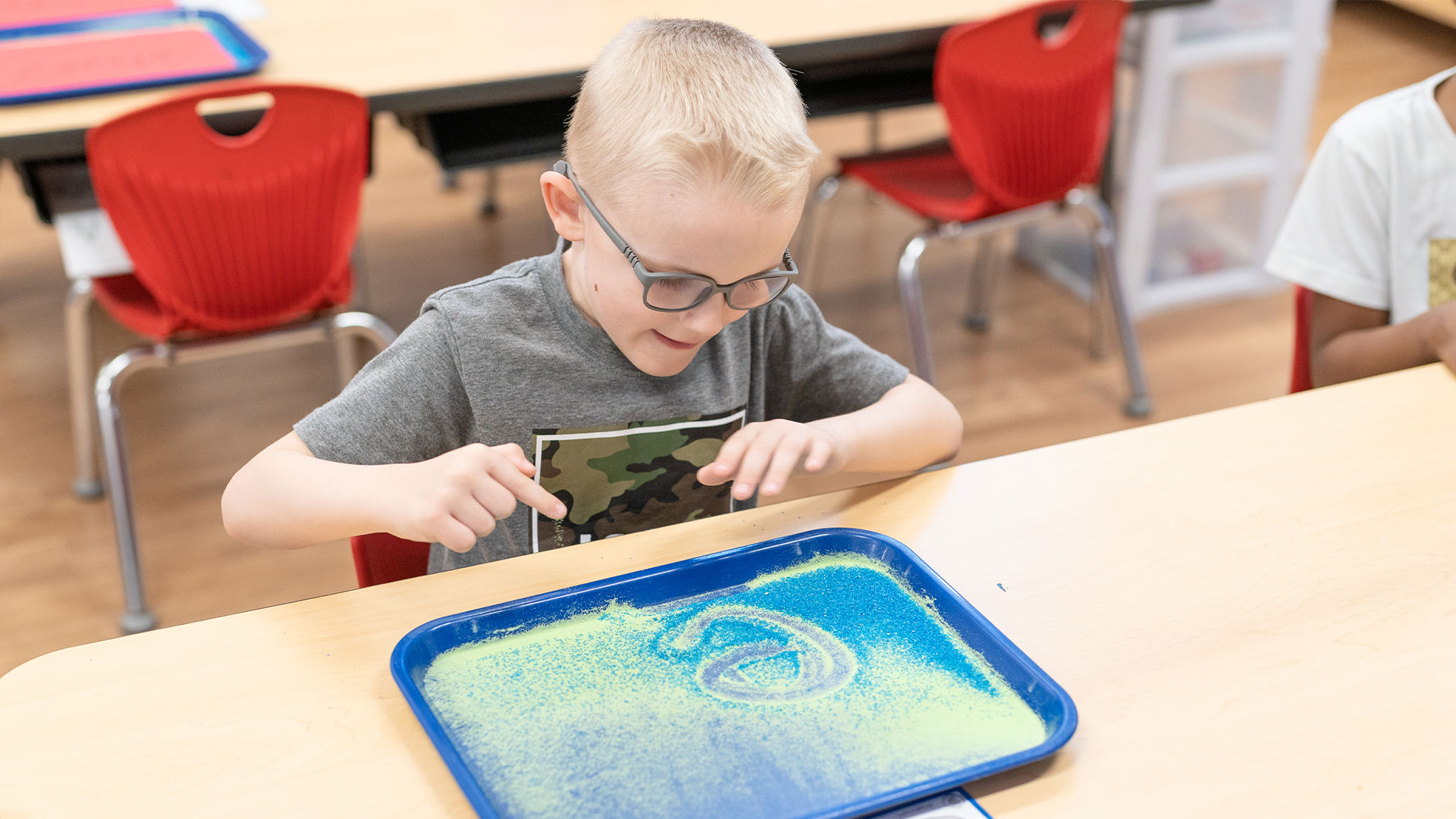 IMSE student using a sand tray for letter formation